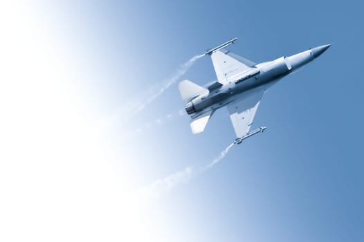 military jet making an aerobatic roll through a gradient blue sky