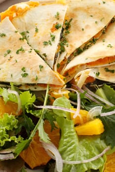 Delicious pumpkin quesadilla sliced and ready to serve with a garden salad.
