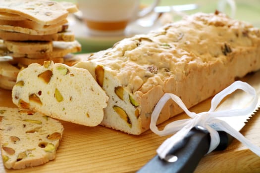 Fresh baked sweet pistachio bread sliced on a bread board with coffee.