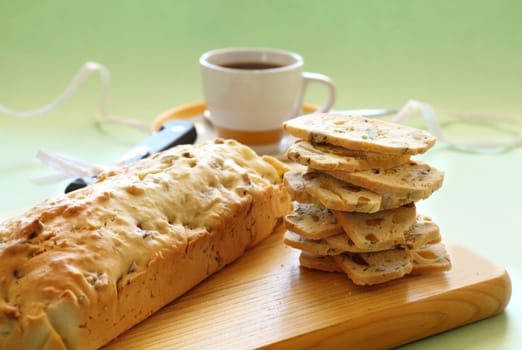 Fresh baked sweet pistachio bread sliced on a bread board with coffee.