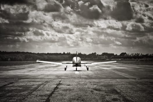 sepia toned propeller aircraft taking off into turbulant looking clouds