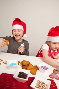 Girls decorating gingerbread cookies at Christmas. Studio shot.