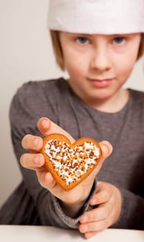 Girl holding a heart shaped decorated Christmas gingerbread