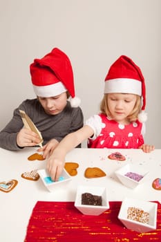 Girls decorating gingerbread cookies at Christmas. Studio shot.