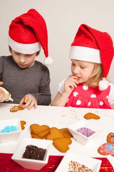 Girls decorating gingerbread cookies at Christmas. Studio shot.