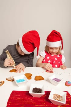 Girls decorating gingerbread cookies at Christmas. Studio shot.