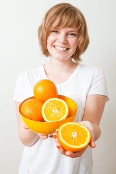 Young woman holding a bowl of fresh oranges. Studio shot.