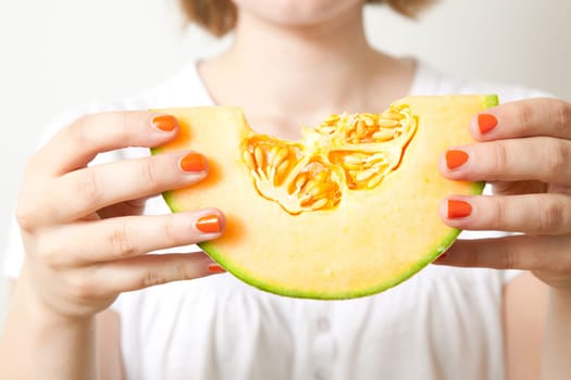 Young woman holding a piece of fresh cantaloupe melon