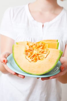 Young woman holding a piece of fresh cantaloupe melon