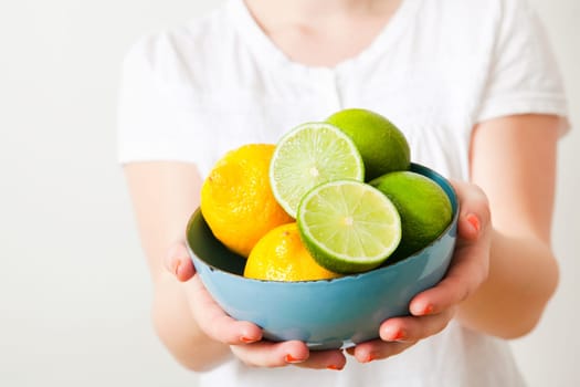 Young woman holding a bowl of fresh lemon and lime