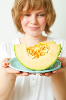 Young woman holding a piece of fresh cantaloupe melon