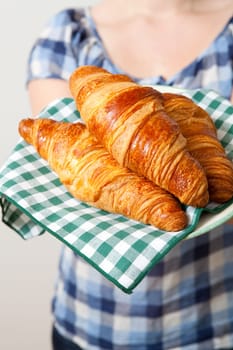 Young woman holding a plate of croissants