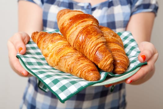 Young woman holding a plate of croissants