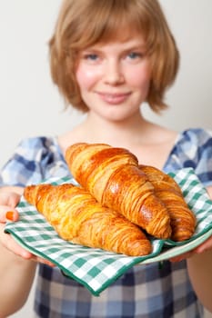 Young woman holding a plate of croissants