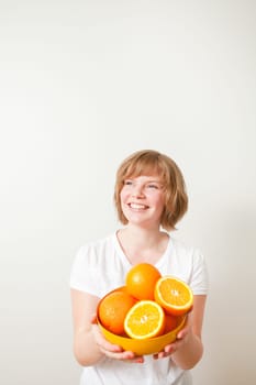 Young woman holding a bowl of fresh oranges. Studio shot.