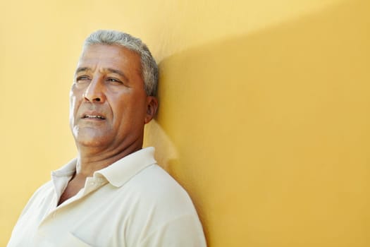 portrait of 50 years old latin american man having problems and leaning on yellow wall. Horizontal shape, copy space