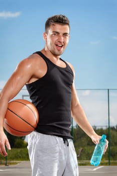 Thirsty basketball player drinking water on sports field