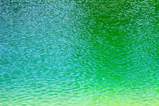 Green aqua water of a reservoir ripples in the sunshine on a summer day.