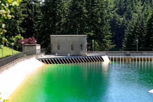 Outdoor historic reservoir with green blue water set in a beautiful landscaped setting in the summer sun.