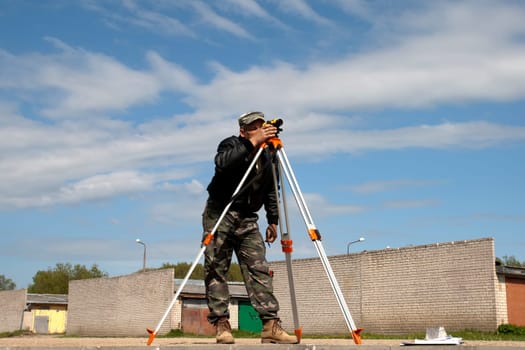Surveyor measuring land for new street build.