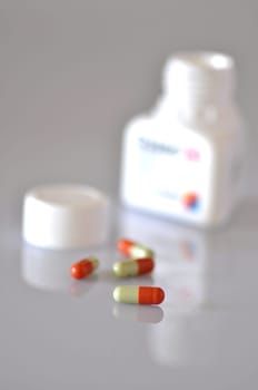 colourful capsules spilling from a plastic bottle
