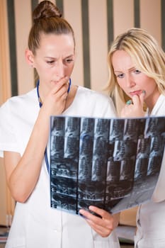 women doctors reading MRI film scans of patient&#039 s spine