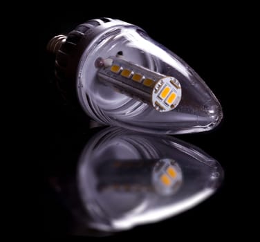 Latest LED light bulb in candle shape and reflecting off a black surface