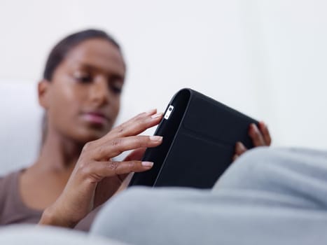 close up of mid adult indian woman relaxing on sofa and using touch pad computer. selective focus, copy space