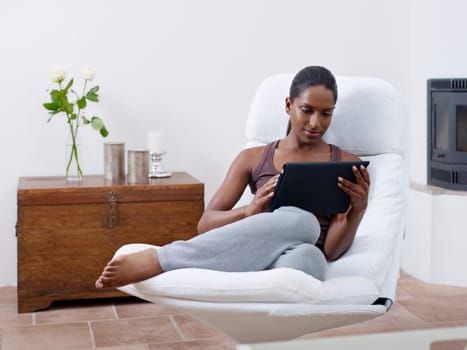 mid adult indian woman relaxing on armchair and using touch pad computer. Horizontal shape, front view, copy space