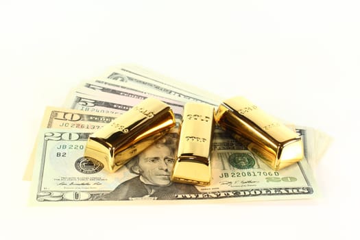 Dollar bills and gold bars against white background