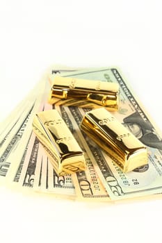 Dollar bills and gold bars against white background