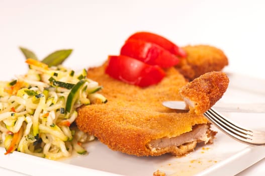 Schnitzel with tomato slices and zucchini salad