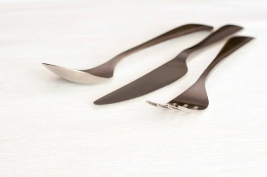 Stainless Fork, knife and spoon on light tablecloth - shallow depth of field