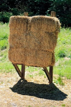 One hay bay backstop for archery targets outdoor in a sunny summer field.