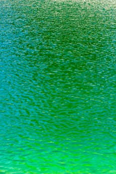 Green aqua water of a reservoir ripples in the sunshine on a summer day.