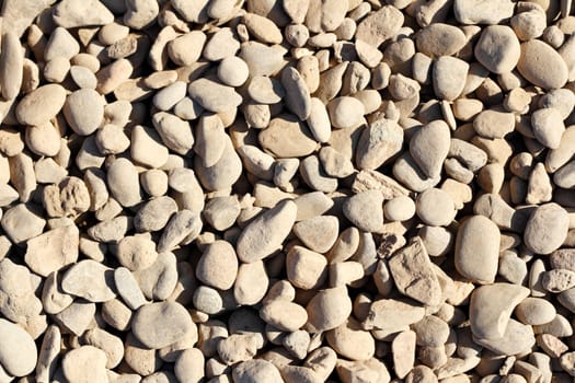 Small tan dirt dusty gray river rock background outdoor in the summer sun.