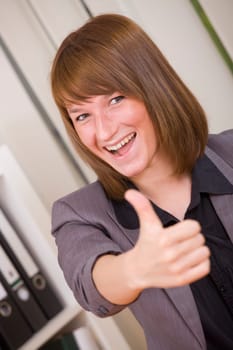 happy businesswoman with thumb up gesture in office
