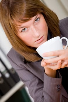 businesswoman having coffee break in office while sitting at desk