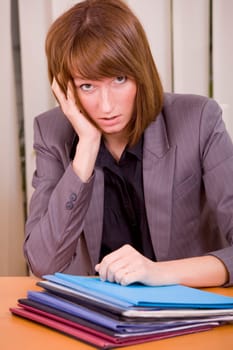 overworked and frustrated woman with files on the desk