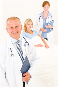 Two medical doctors professional with hospital patient lying in bed