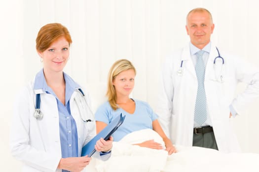Two medical doctors professional with hospital patient lying in bed