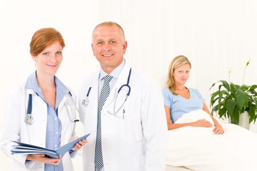 Two medical doctors professional with hospital patient lying in bed