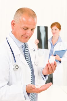 Medical doctor team senior male holding pills young female colleague