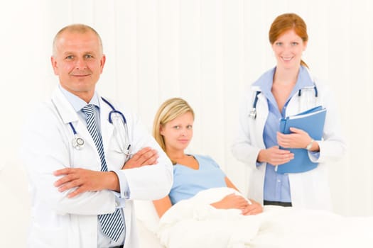 Two medical doctors professional with hospital patient lying in bed