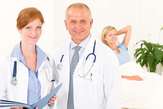 Two medical doctors professional with hospital patient lying in bed