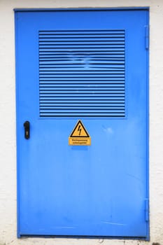 Blue door with warning sign of high voltage on a transformer house