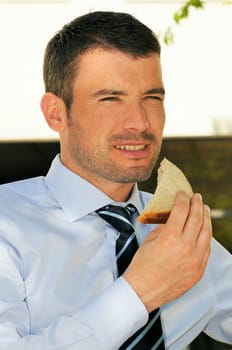attractive businessman is eating a sandwich
