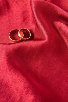 Two wedding rings on red satin background