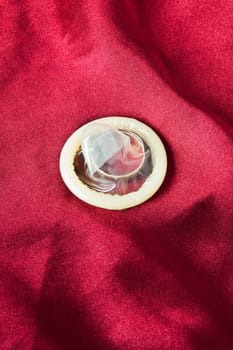 Wedding ring condom in a red satin background