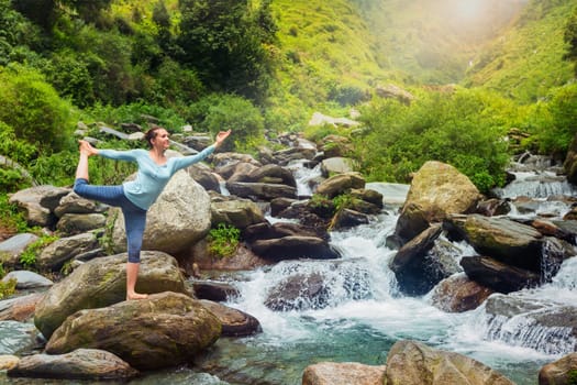 Yoga outdoors - woman doing yoga asana Natarajasana - Lord of the dance balance pose outdoors at waterfall in Himalayas